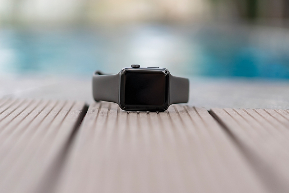 An Apple watch is pictured on the ground. Behind the watch is an indoor pool.